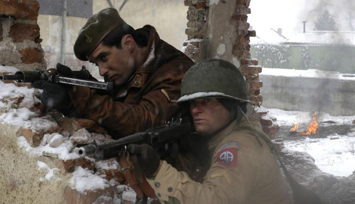 Zwei Soldaten im Schnee suchen Deckung hinter einer Mauer und halten Waffen.