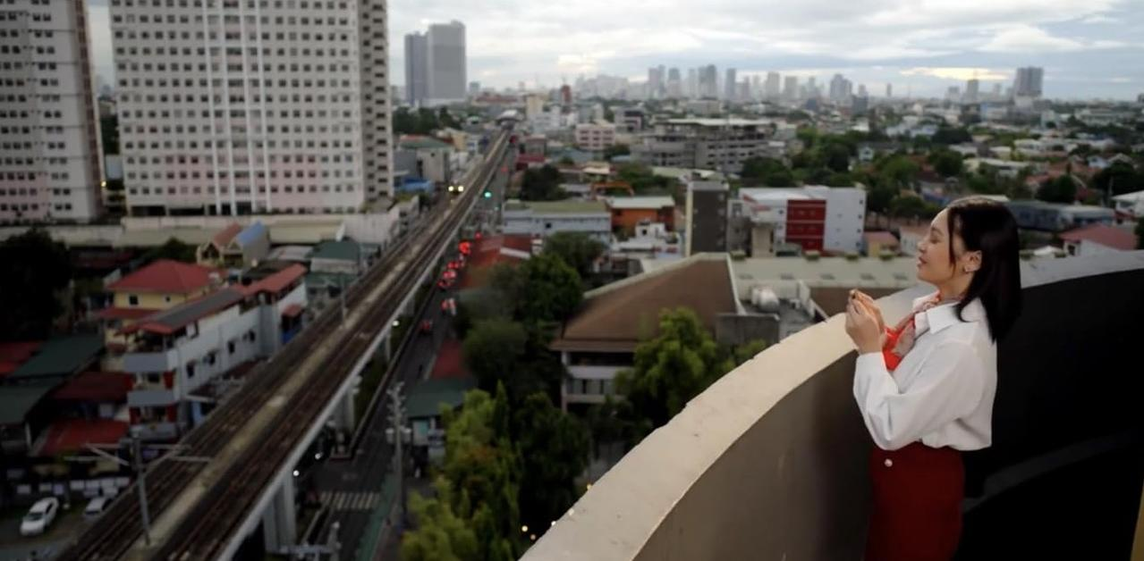 Frau steht auf einem Balkon mit Blick auf eine Stadt und Bahngleise.
