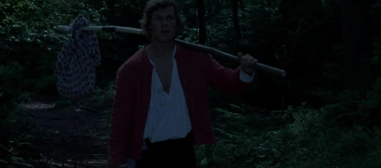 Ein Mann mit einem Bündel auf einem Stock geht durch einen dunklen Wald.