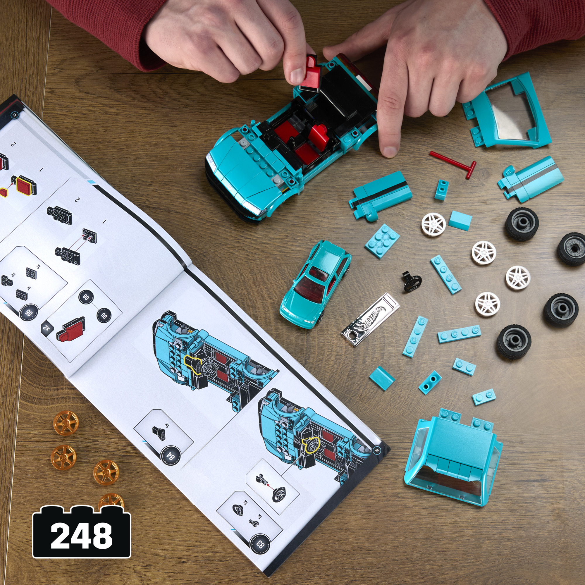 Bauanleitung für ein blaues Auto mit roten Sitzen, Teile und Räder liegen verstreut.