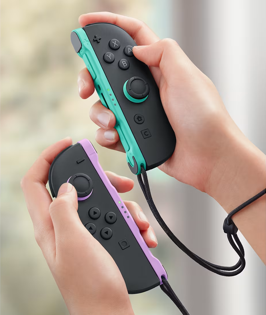 Hände halten zwei Joy-Con-Controller in Schwarz mit türkisen und lila Akzenten.