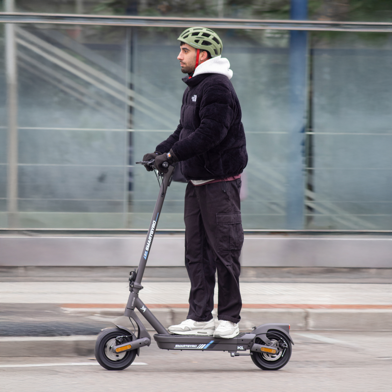 Un hombre con casco monta un patinete eléctrico en una calle.
