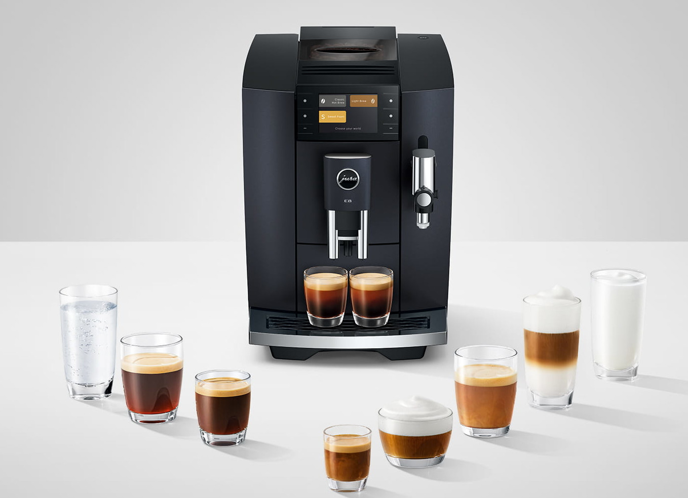 Ciemny ekspres do kawy z wieloma specjałami kawowymi i szklanką wody.