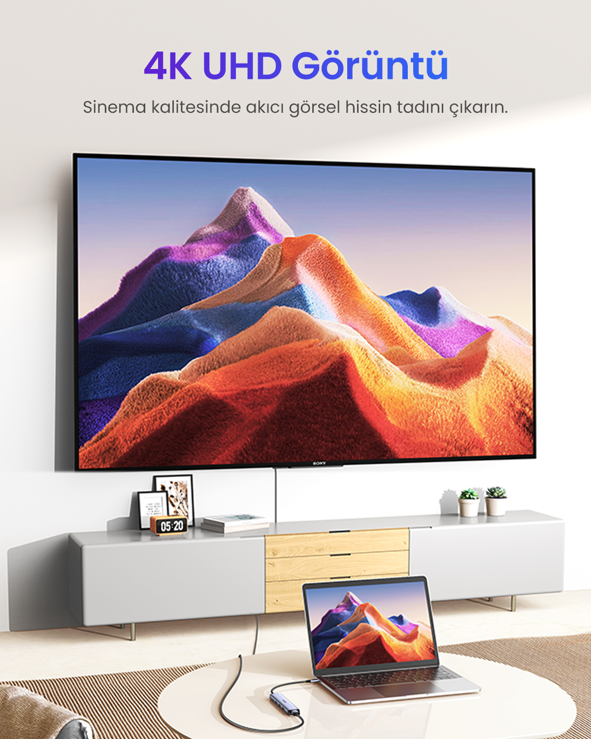 Renkli dağ manzarası gösteren laptop, televizyona bağlı.