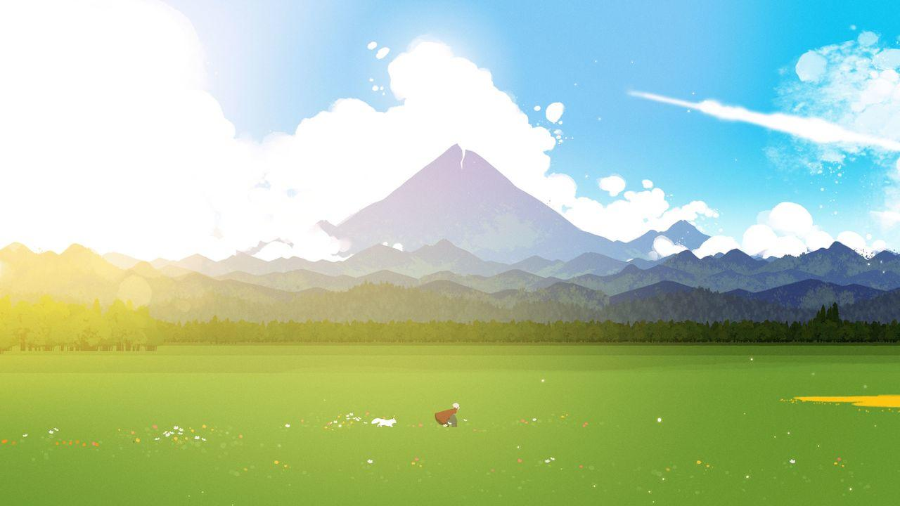 Eine Person und ein Hund auf einem grünen Feld vor Bergen und blauen Himmel.