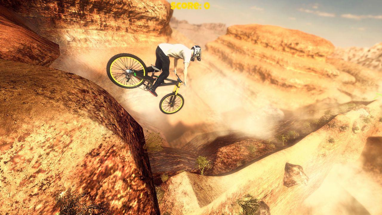 Ein Mountainbiker springt über eine Schlucht in einer Wüstenlandschaft.