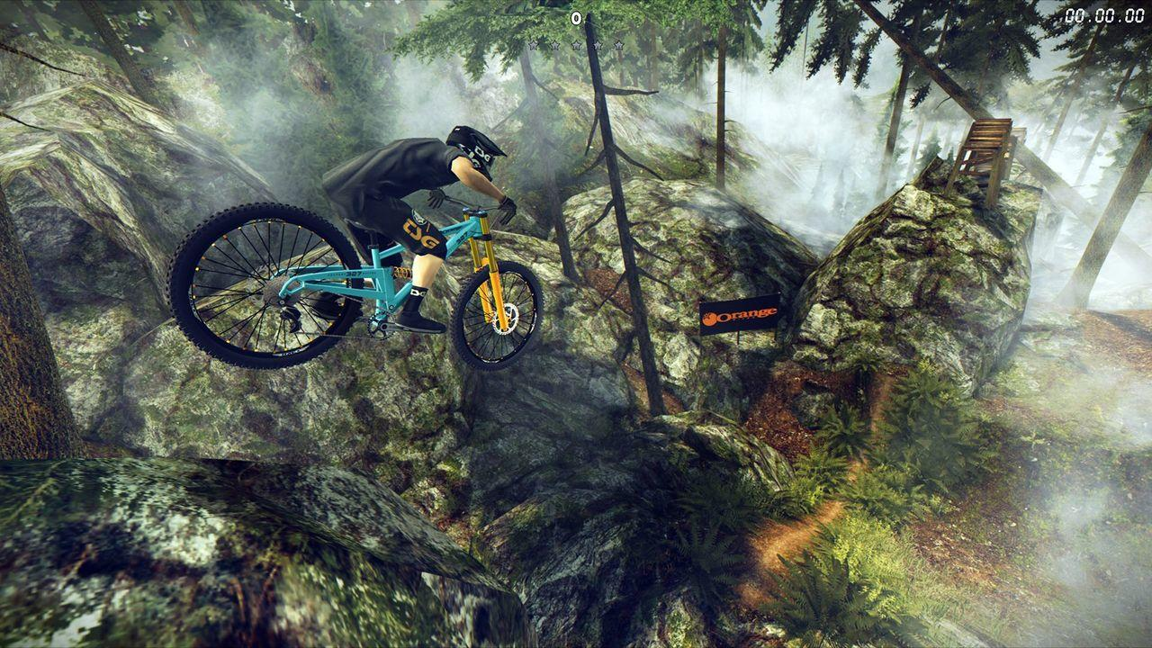 Ein Mountainbiker springt in einer nebligen Berglandschaft über Felsen.