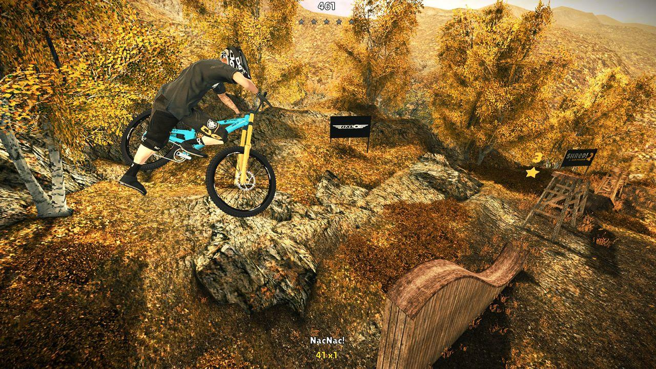 Ein Mountainbiker fährt einen steinigen Hang mit gelben und braunen Bäumen im Hintergrund.