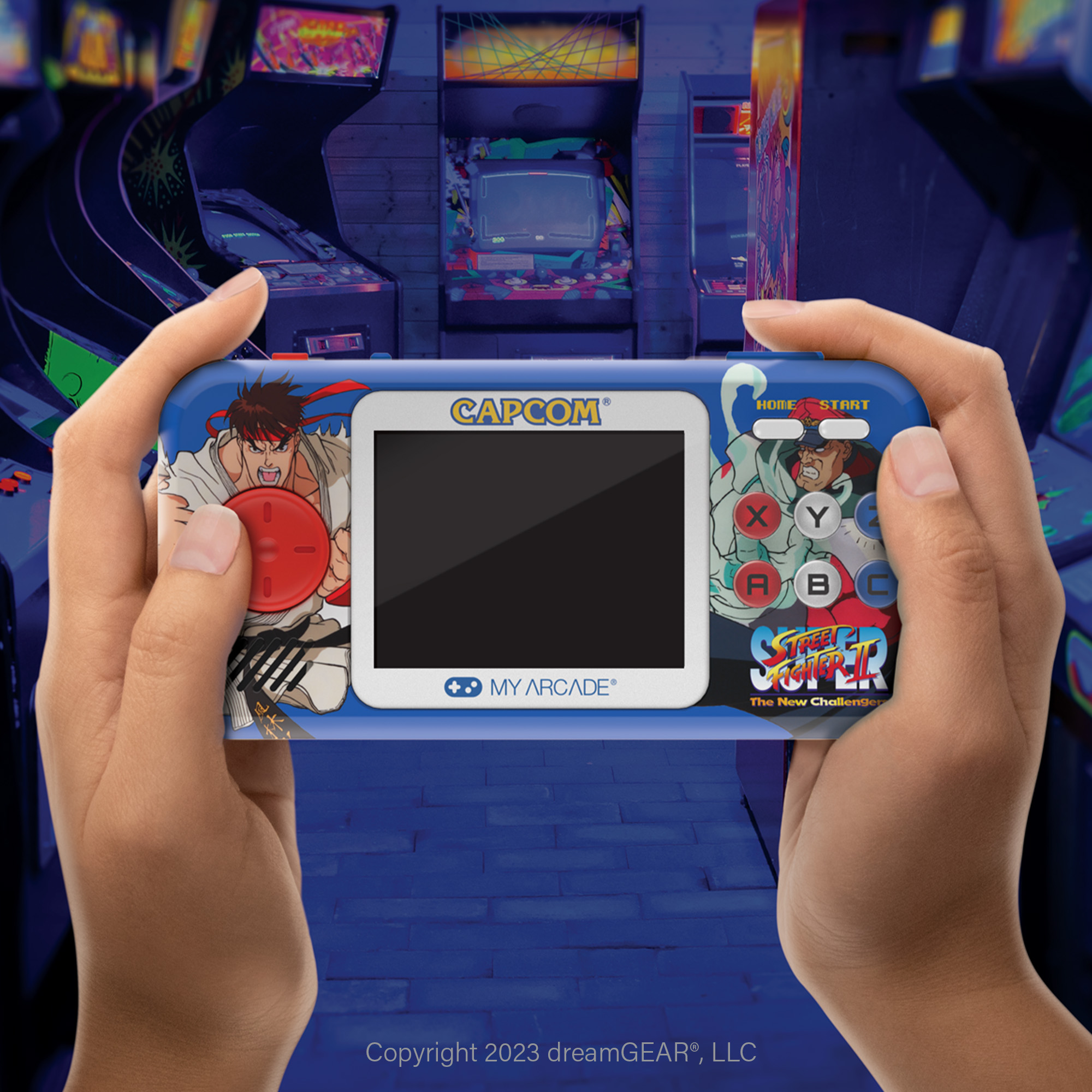 Eller, arkada atari makineleriyle birlikte Street Fighter karakterlerinin yer aldığı mavi bir Capcom elde taşınır tutuyor.