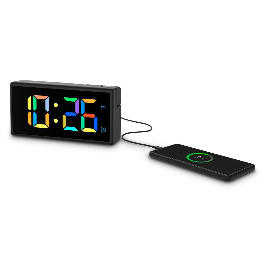 Ein digitaler Wecker zeigt 10:26 PM an, verbunden mit einem schwarzen Smartphone auf einer Ladestation.