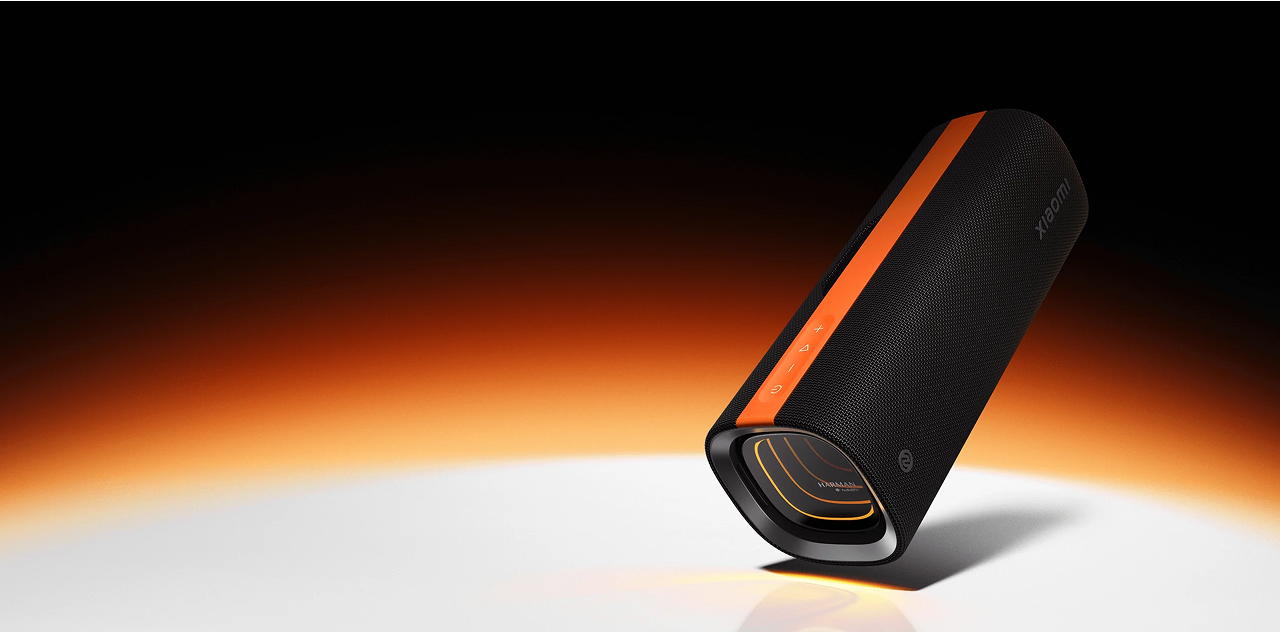 Czarny głośnik z pomarańczowym paskiem, świecącymi akcentami i przyciskami.
