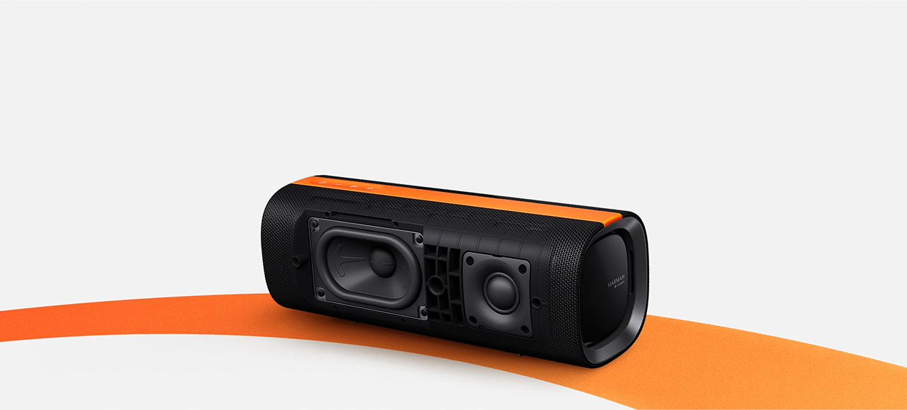 Czarny głośnik z pomarańczowymi akcentami i widocznymi przetwornikami.
