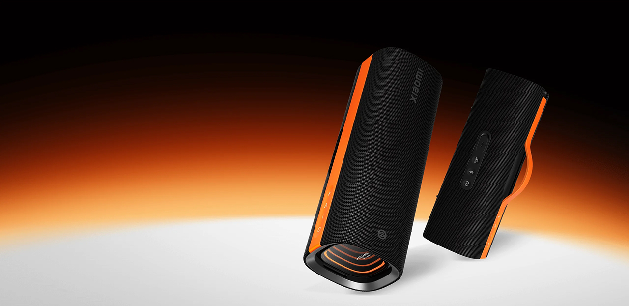 Dwa czarne głośniki z pomarańczowymi akcentami na białej powierzchni.