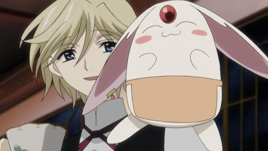 Blonder Anime-Junge mit blauen Augen hält eine Tasse, neben ihm ein weißes Kaninchen-ähnliches Wesen.