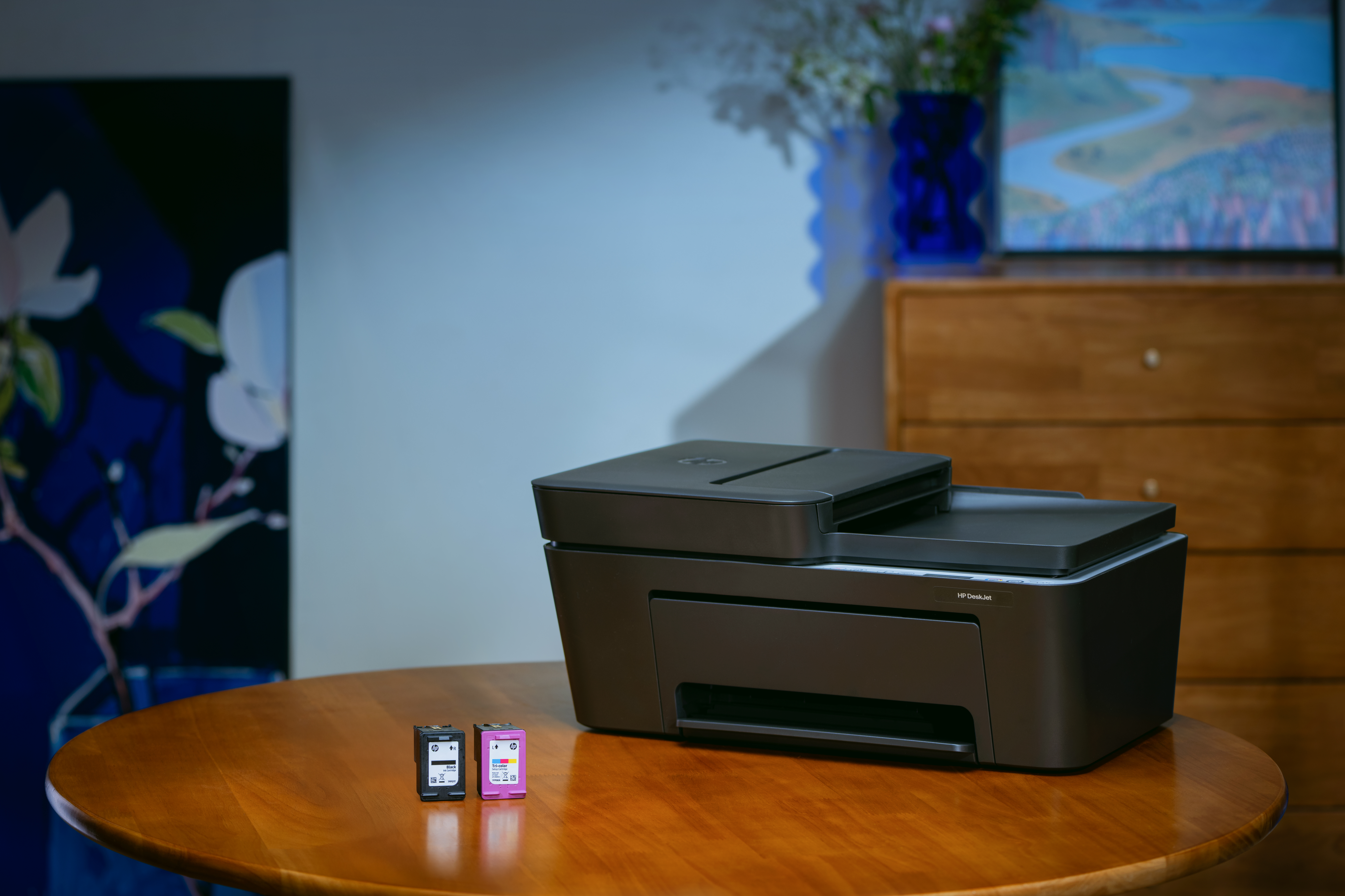 Czarna drukarka stoi na drewnianym stole z dwoma wkładami atramentowymi obok.