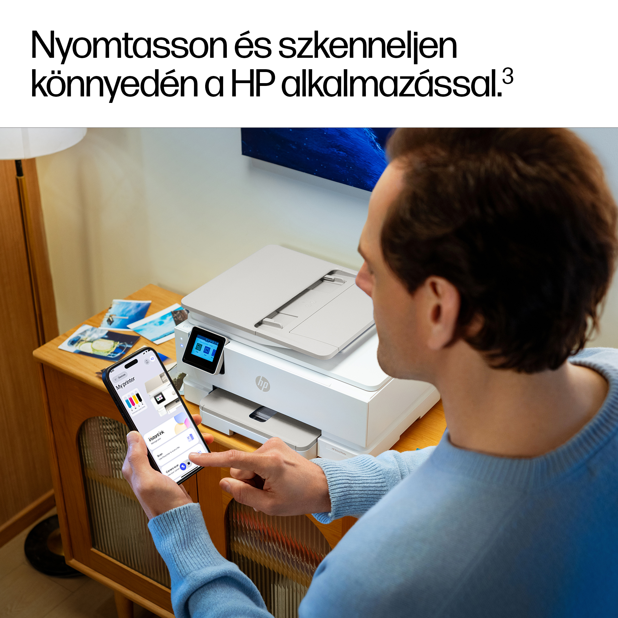 Férfi HP nyomtatót használ okostelefonos appal. Fényképek az asztalon.