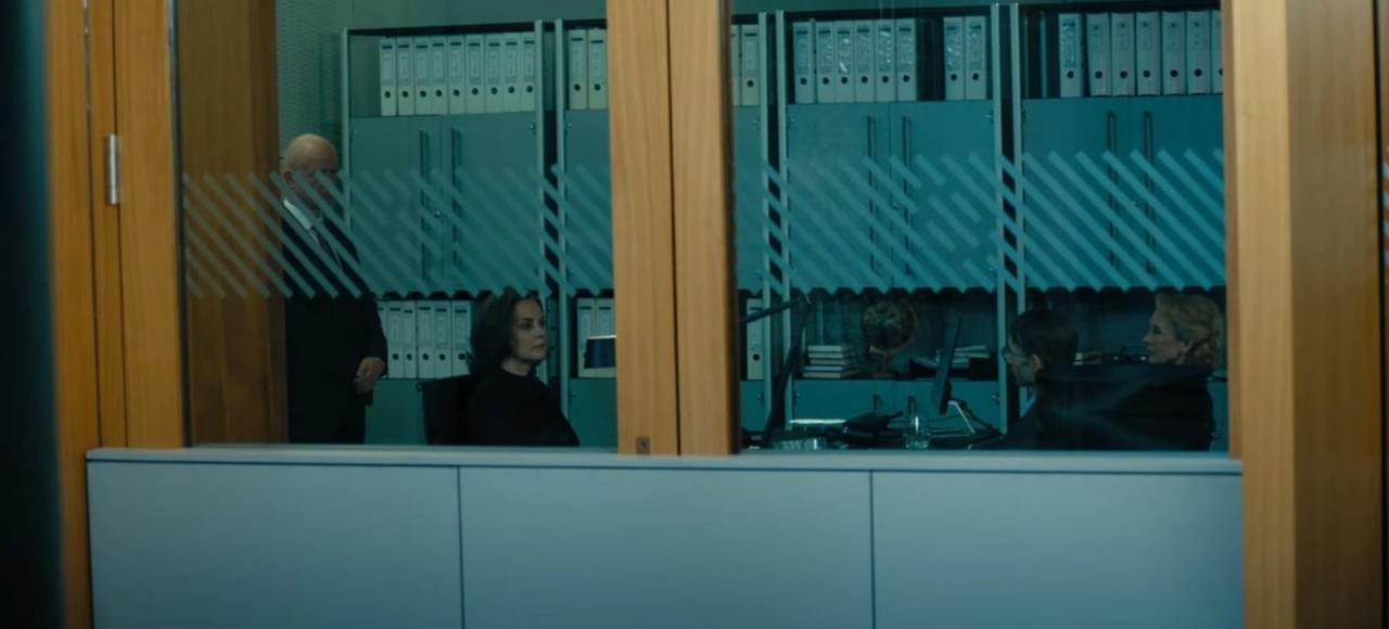 Ein Mann in einem Anzug geht an einem Büro vorbei, in dem Frauen sitzen.