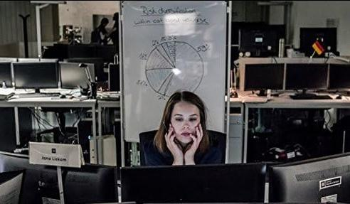 Frau blickt auf Computerbildschirm vor Whiteboard mit Diagramm. Büroumgebung.