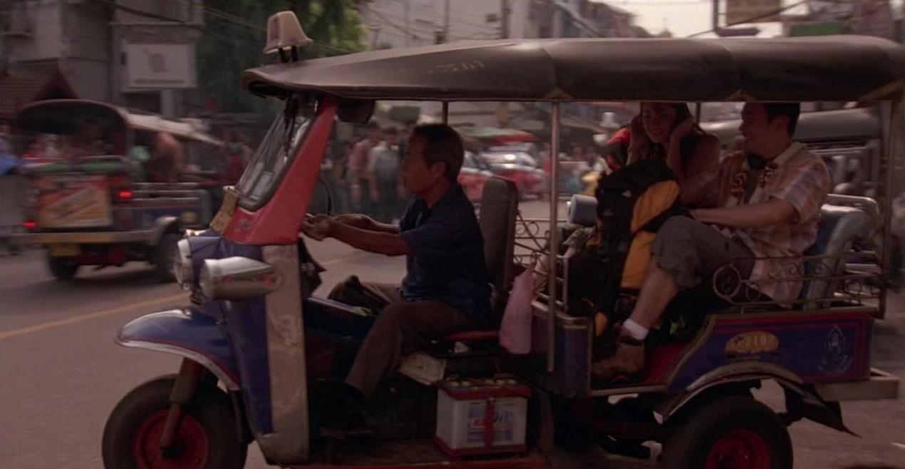 Ein Tuk-Tuk fährt auf einer Straße mit Passagieren und einem Fahrer.