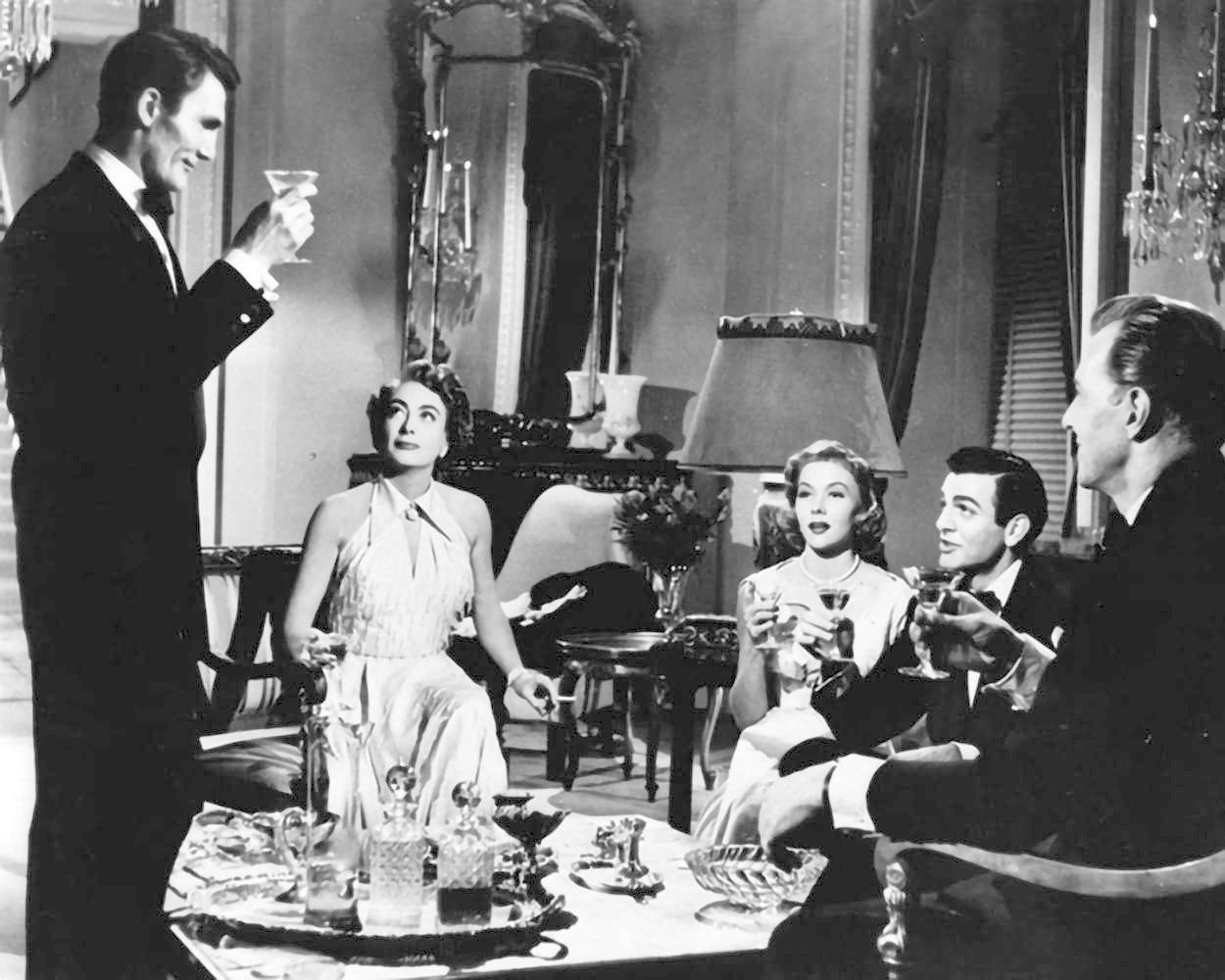 Fünf Personen in formeller Kleidung trinken Cocktails in einem eleganten Raum.