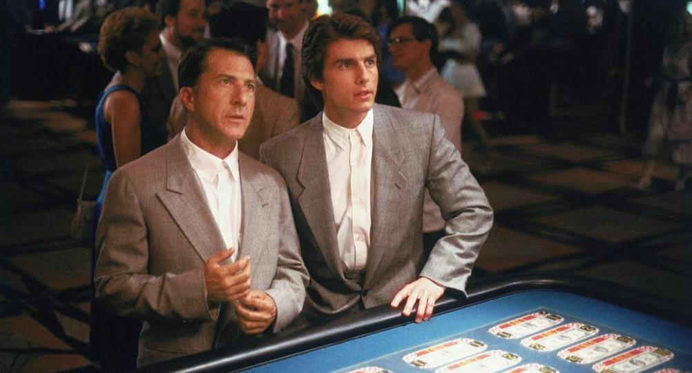 Zwei Männer in Anzügen stehen an einem Spieltisch im Casino. Der Hintergrund ist unscharf.