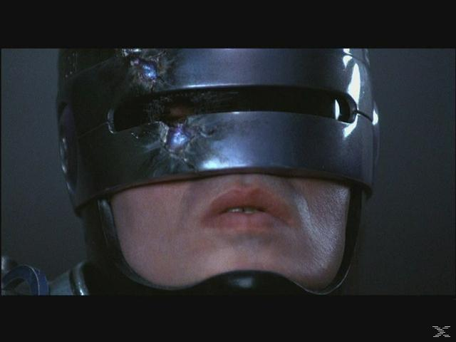 RoboCop mit beschädigtem Helm und sichtbarem Mund, Nahaufnahme.