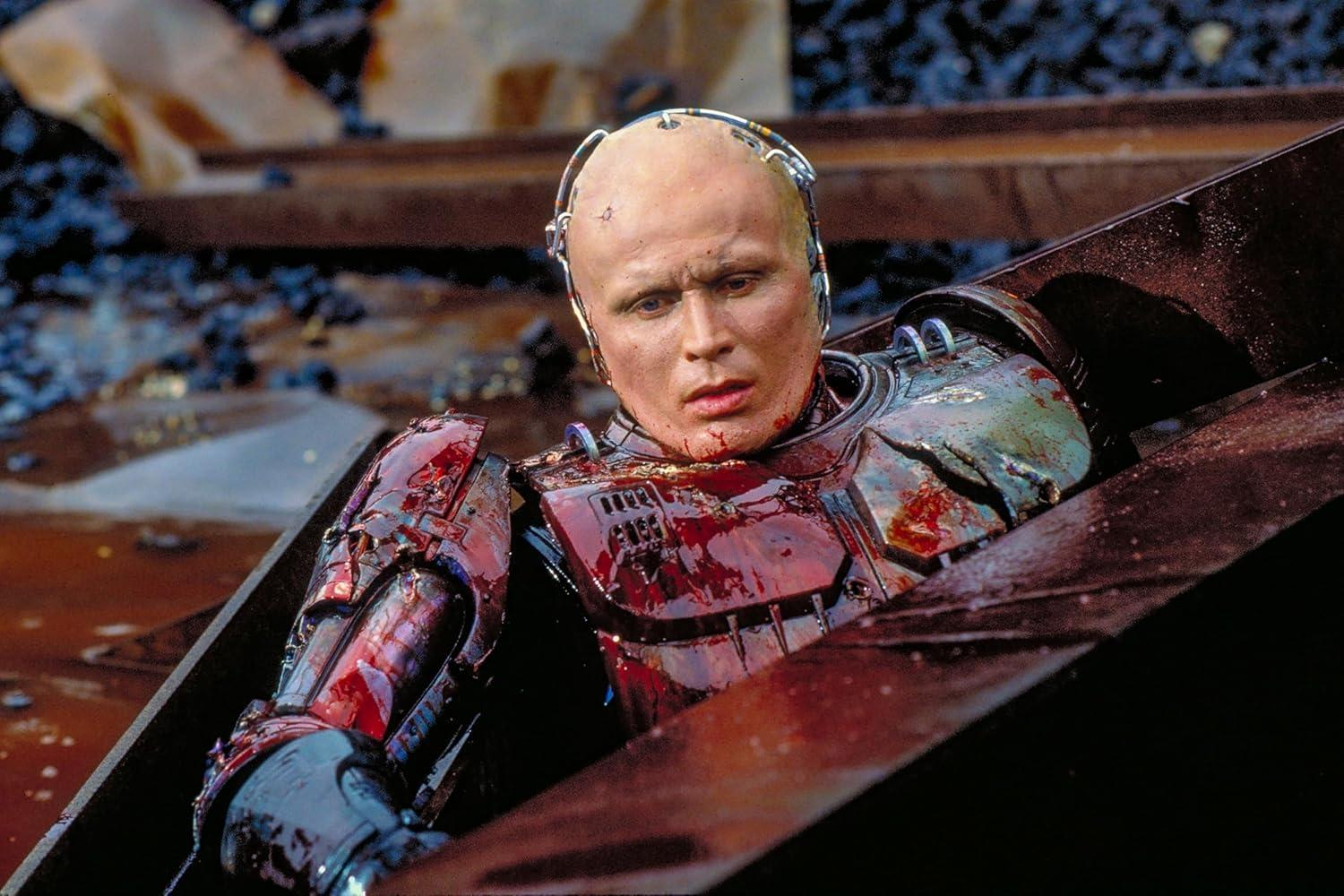 Ein blutiger Cyborg in einem Metallsarg, bedeckt mit Öl und Schutt.