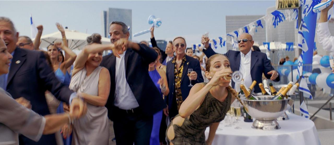 Feiernde Menschen tanzen und trinken Champagner. Israelische Flaggen und Ballons sind zu sehen.