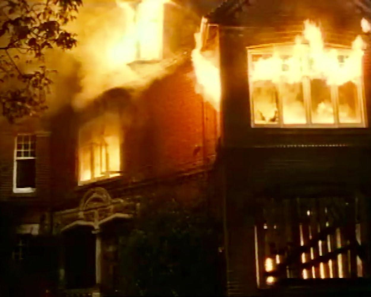 Ein Haus steht in Flammen, Rauch steigt aus den Fenstern auf.