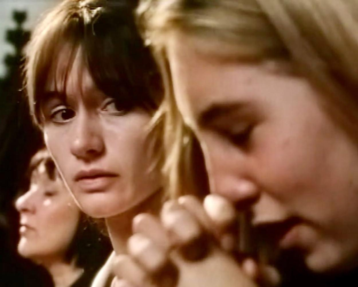 Drei Frauen im Vordergrund, eine blickt nach links, die anderen sind vor ihr.