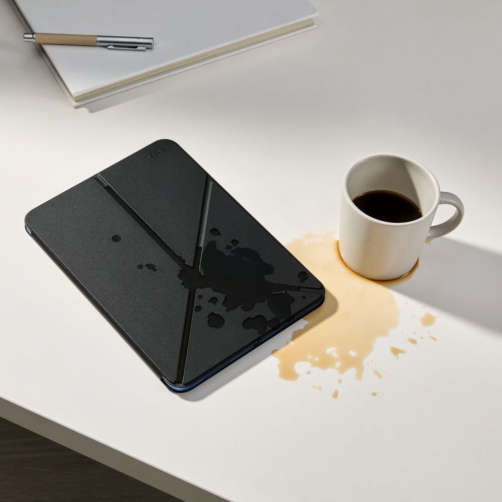 Czarna okładka na tablet z plamami kawy obok filiżanki.