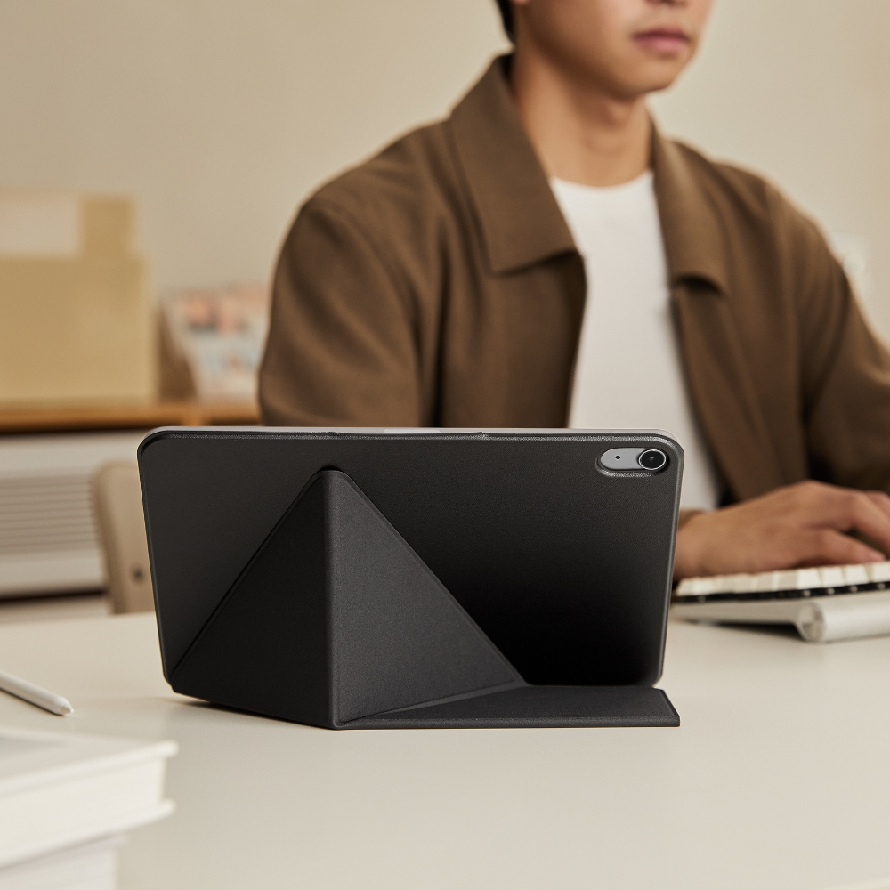 Czarny tablet na stojaku przed mężczyzną w brązowej kurtce.