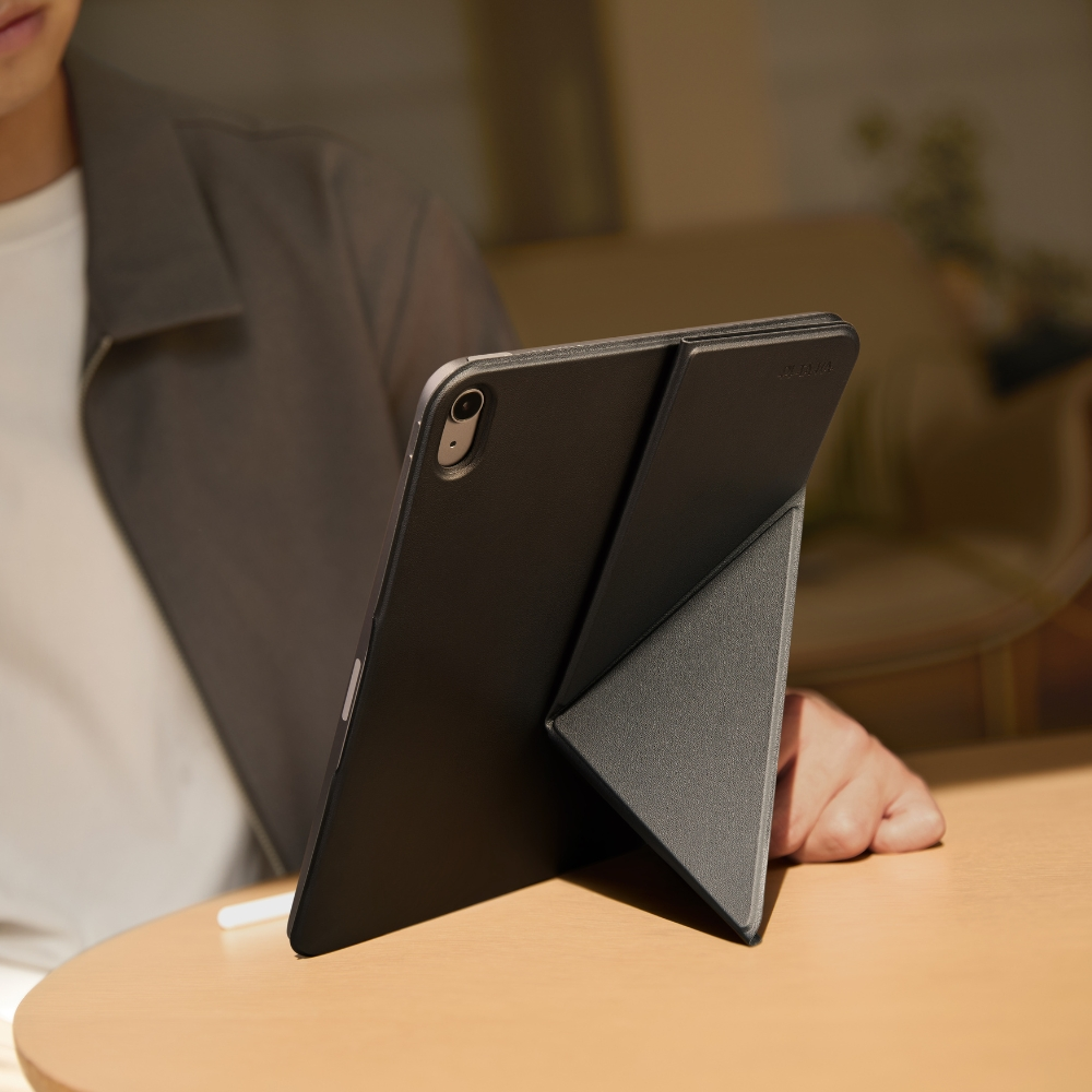 Czarny tablet z podpartą obudową stoi na drewnianym stole.