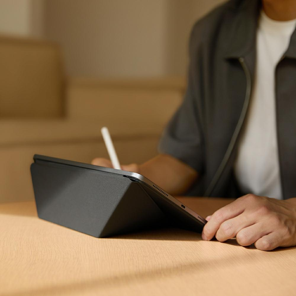 Osoba używająca tabletu ze stylusem na drewnianym stole.