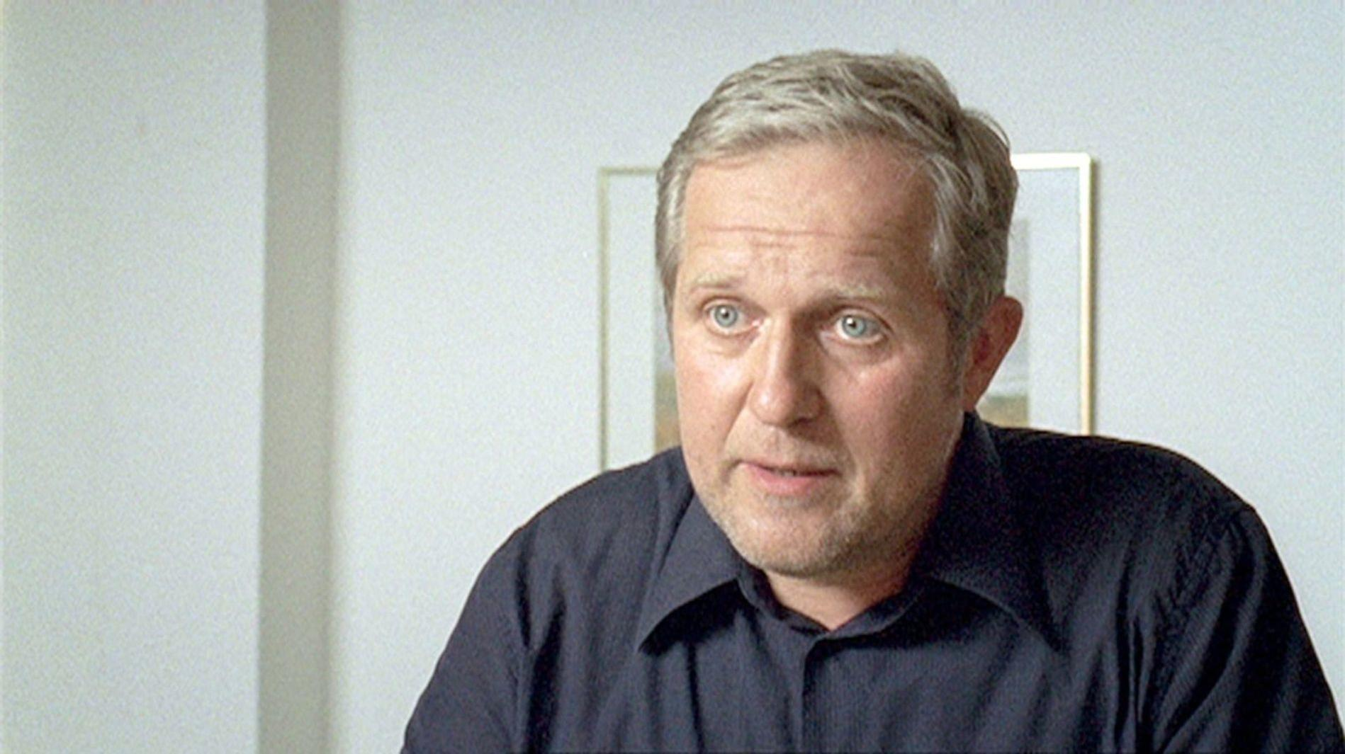Ein Mann mit grauem Haar und blauen Augen trägt ein dunkles Hemd.