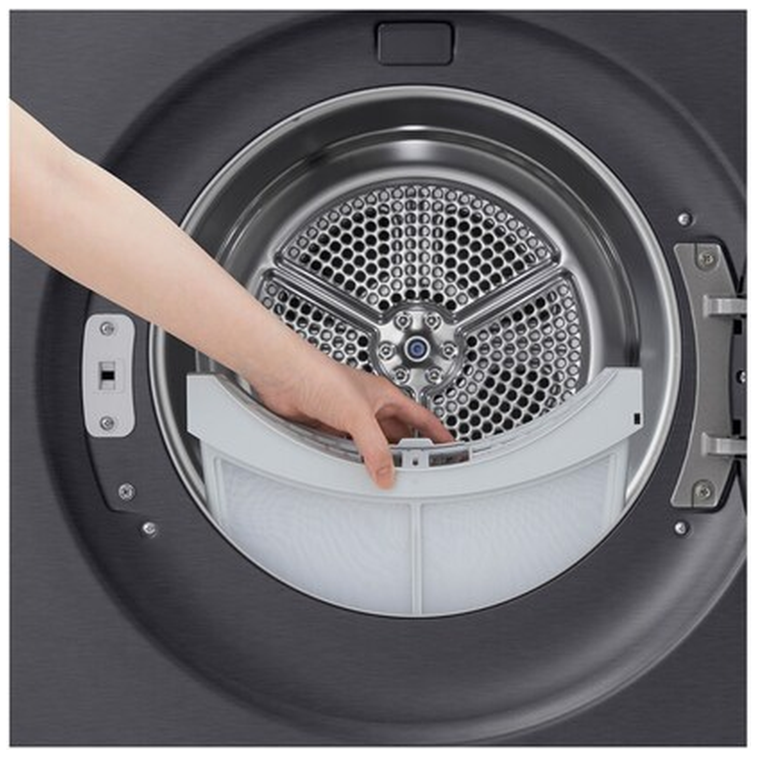 A hand pulls a white lint filter from a dark dryer drum.
