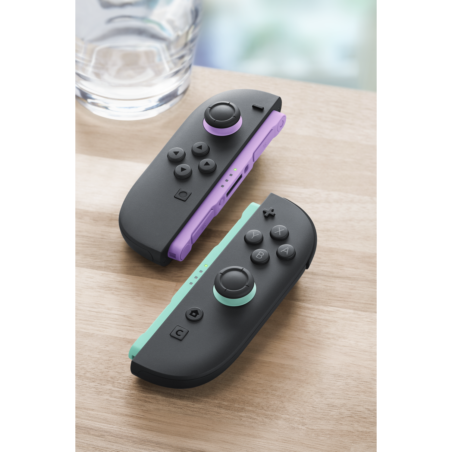 Two black controllers with purple and mint accents on a wooden table.