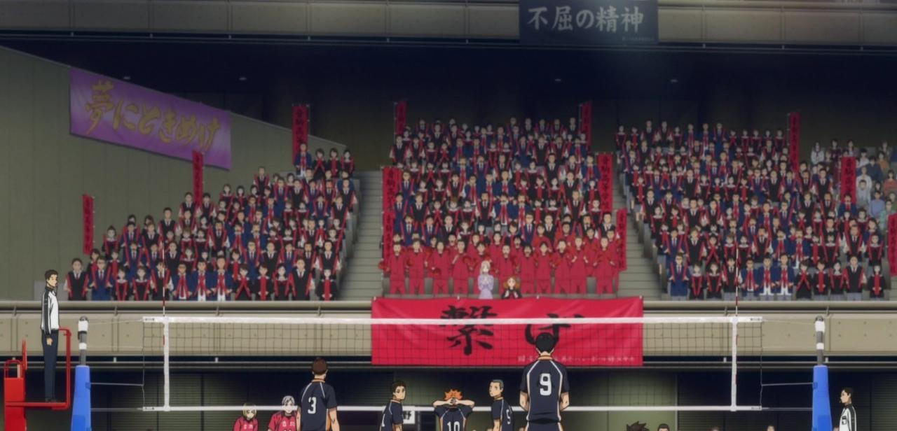 Ein Volleyballspiel mit Zuschauern in roten und blauen Uniformen.