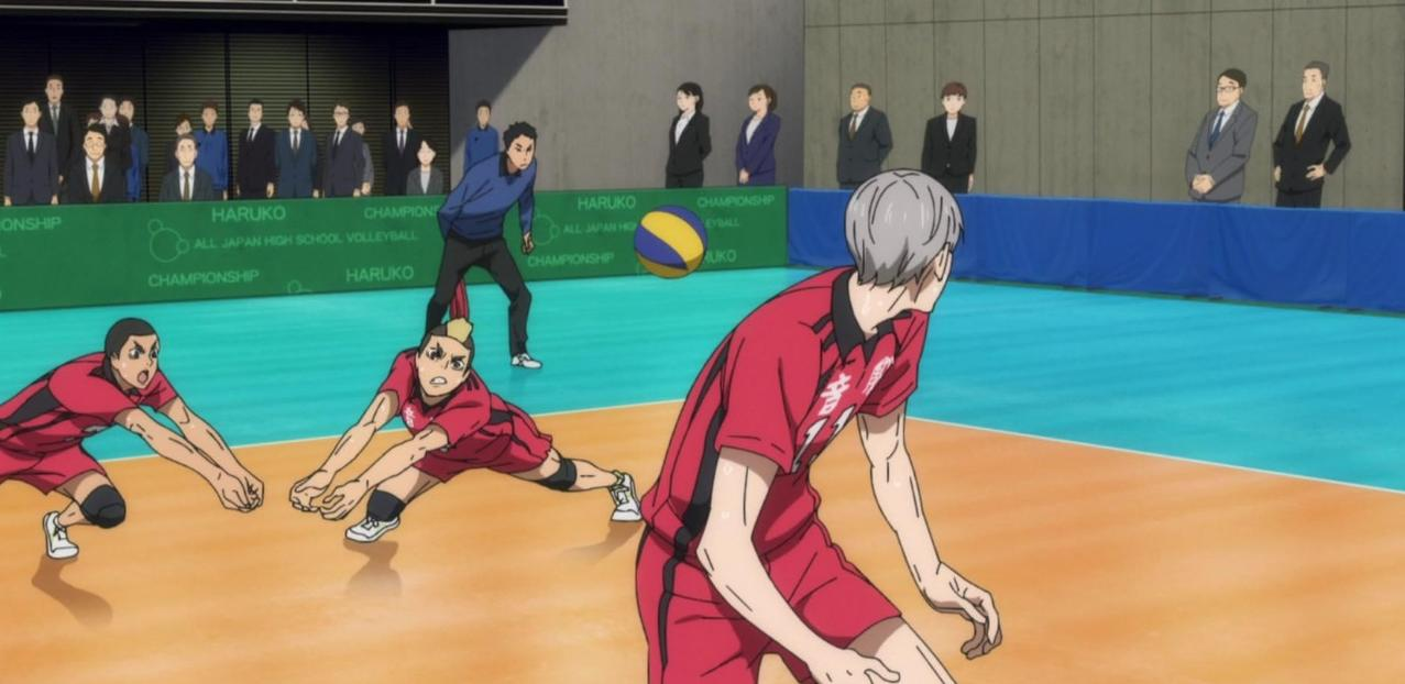 Volleyballspieler in roten Trikots spielen auf einem Hallenplatz vor Zuschauern.