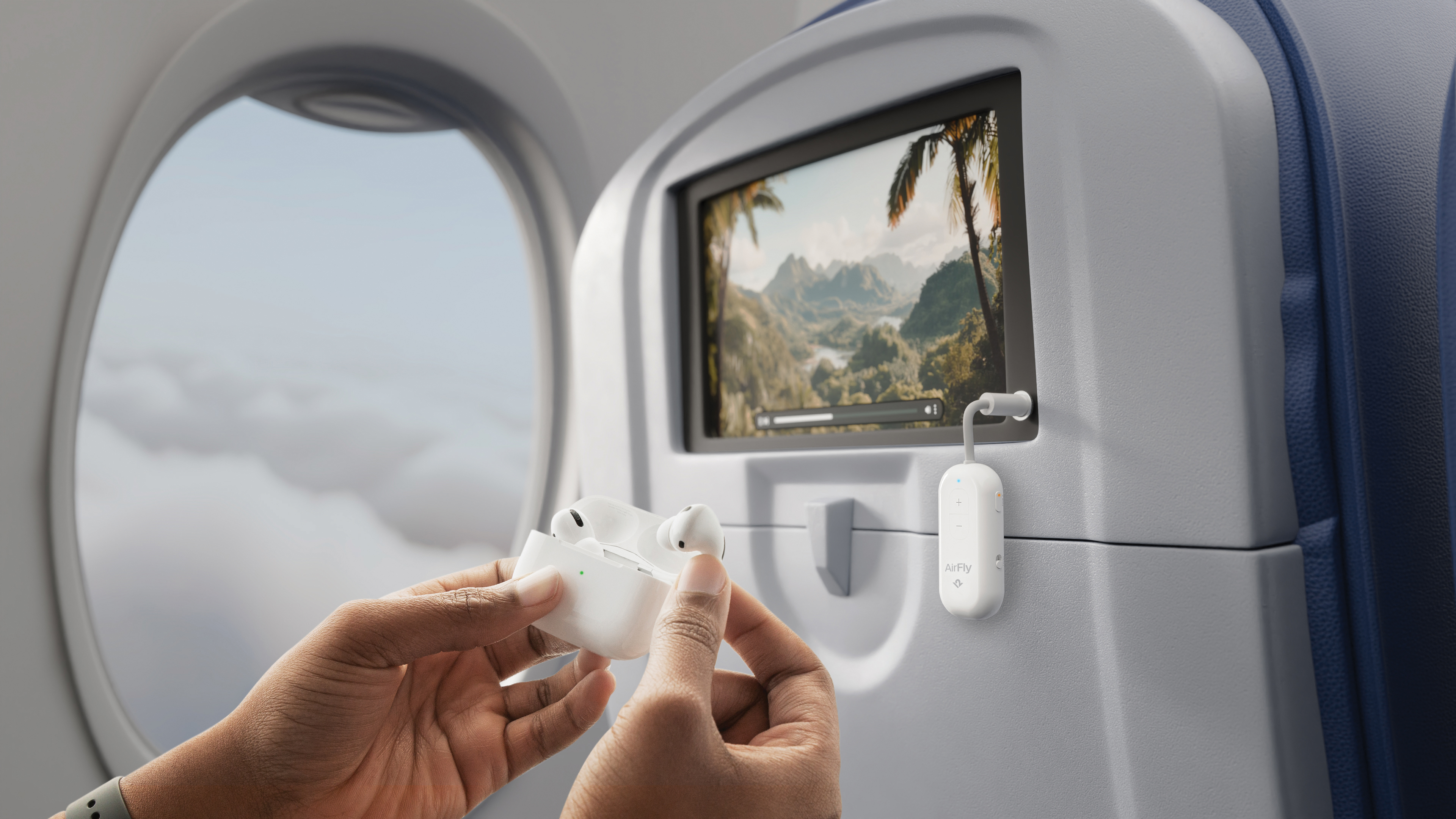 Mains tenant des écouteurs blancs et un étui dans un avion avec vue écran.