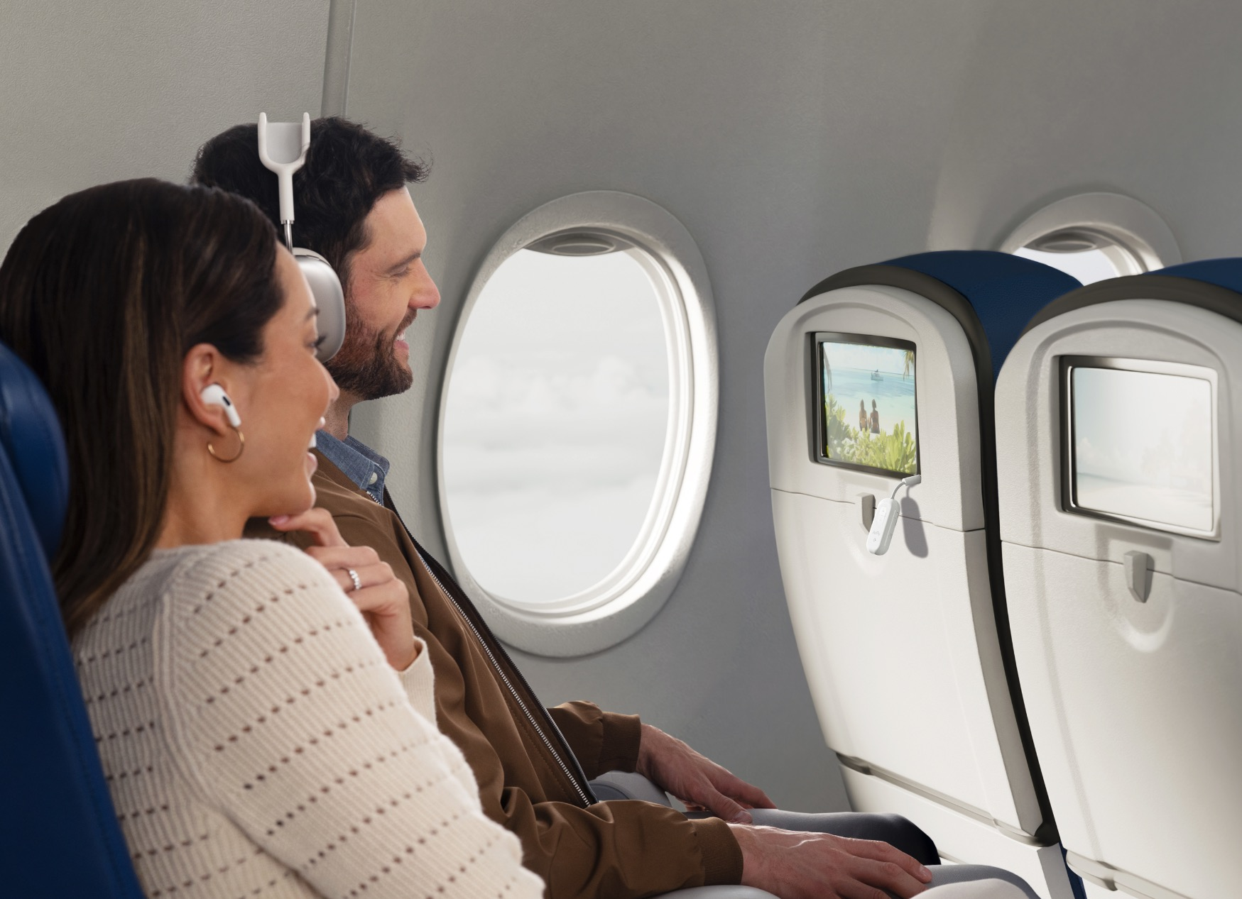 Couple dans un avion, femme avec écouteurs, homme avec écouteurs, regardant l'écran.