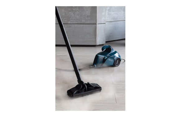 Un limpiador a vapor azul con mango y manguera limpia un piso de madera.