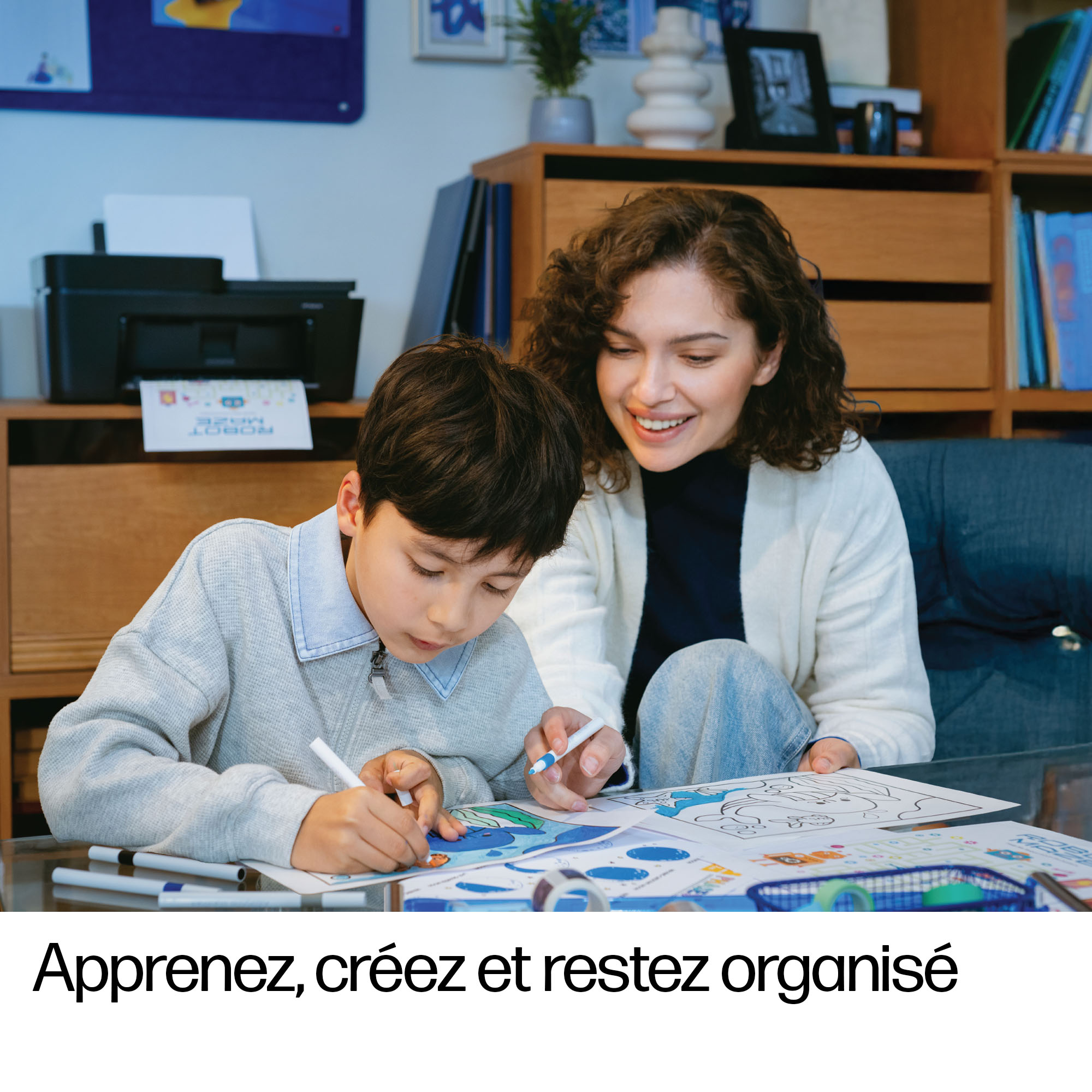 Mère et enfant dessinant et bricolant, imprimante en arrière-plan.