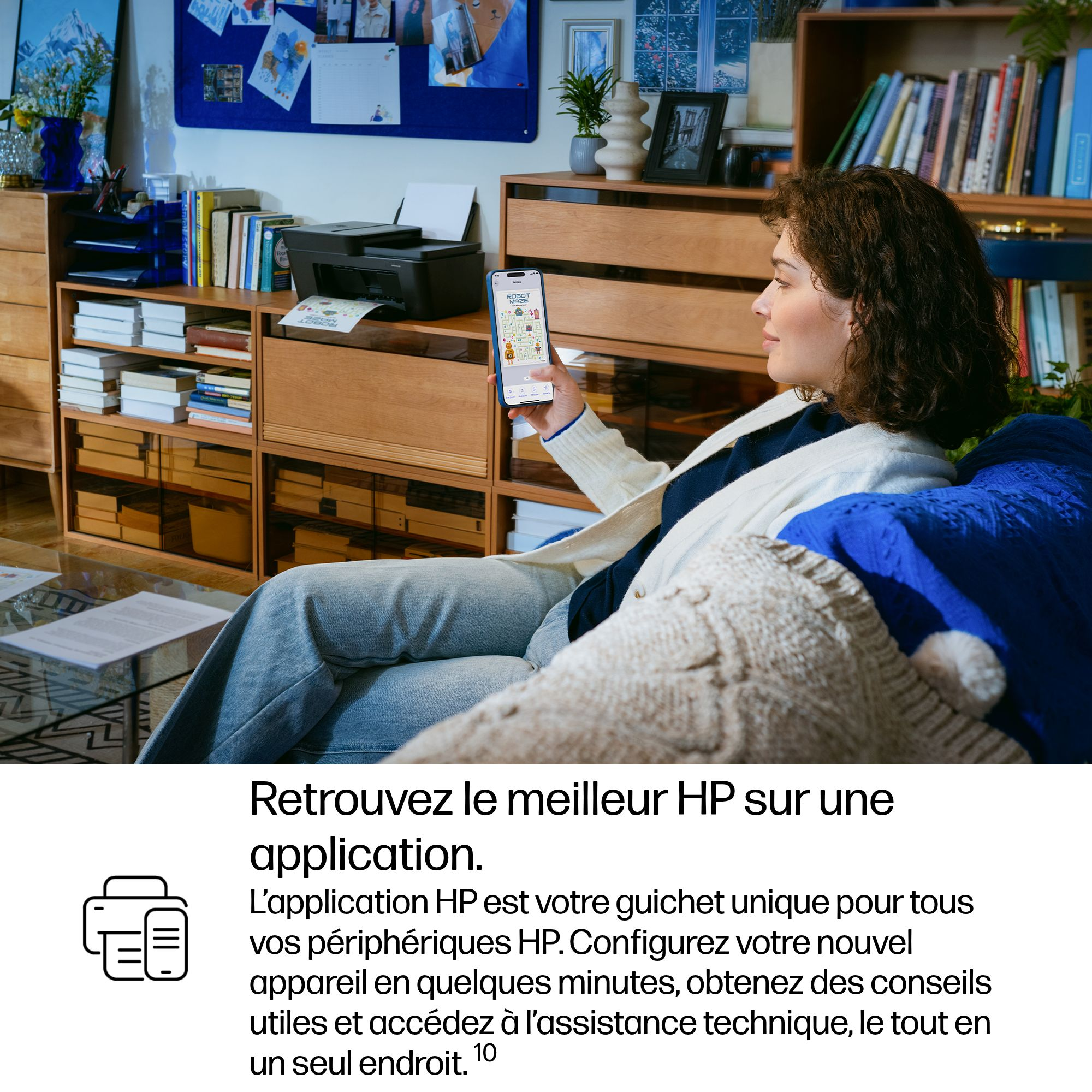 Une femme assise sur un canapé tient un smartphone affichant une application.