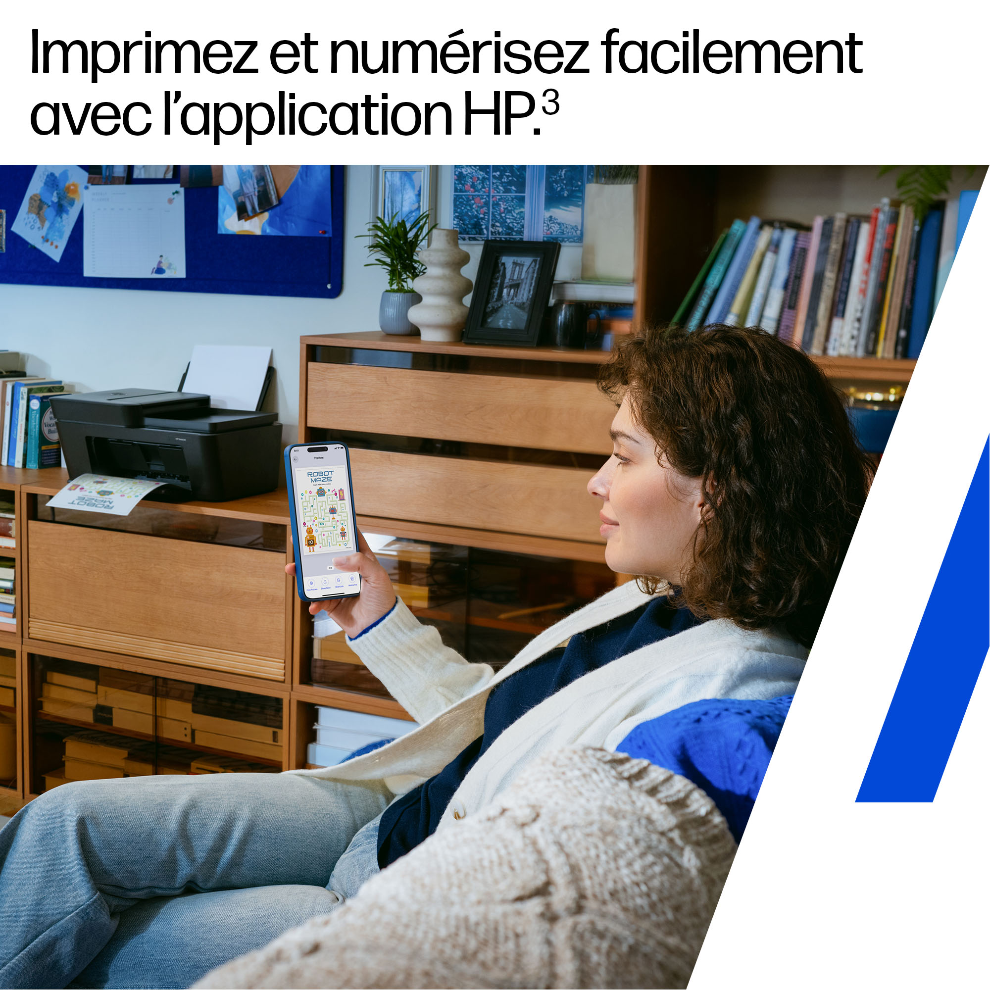 Une femme tient un smartphone montrant un jeu de robot devant une imprimante.