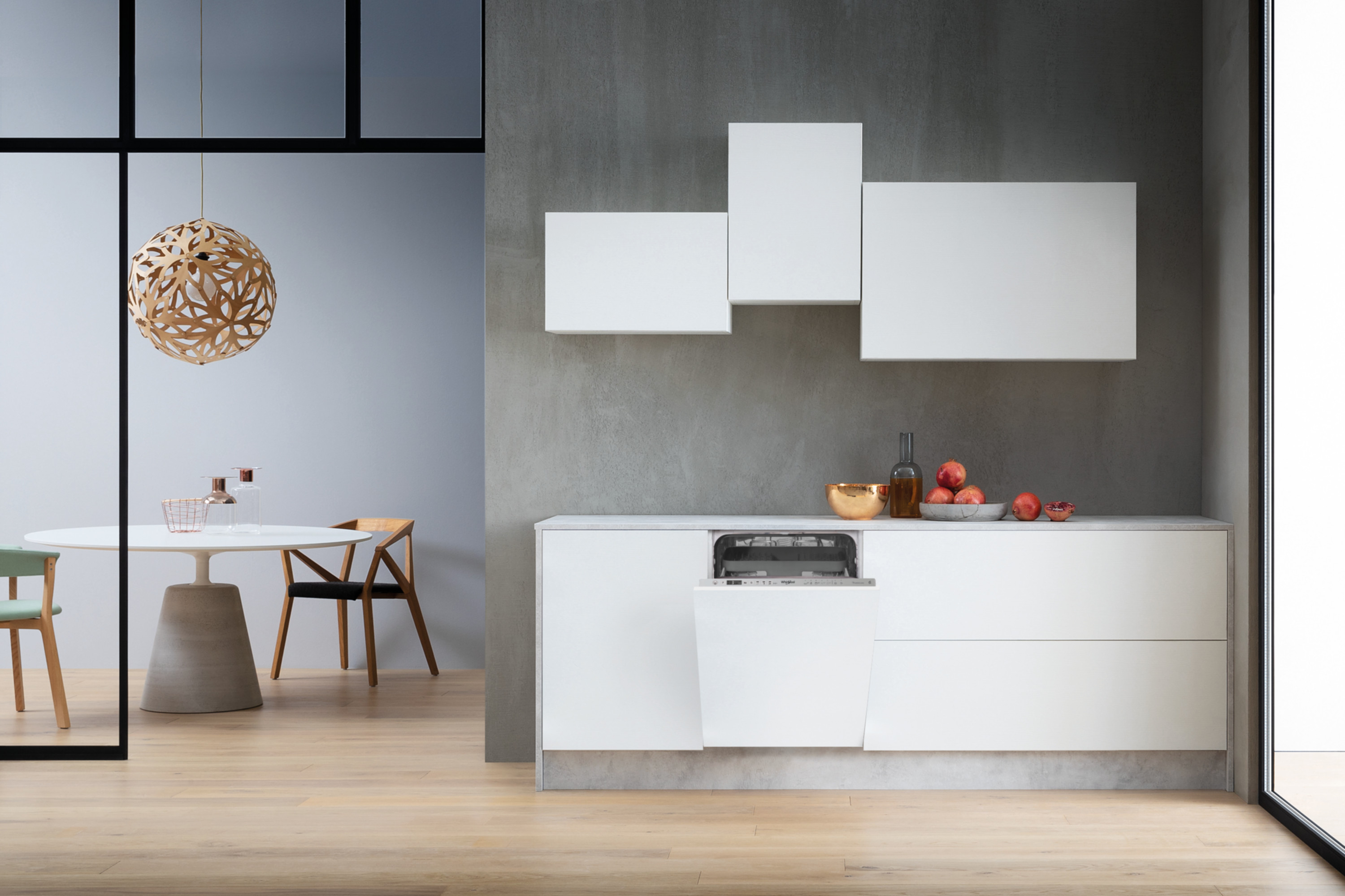 Nowoczesna biała kuchnia z otwartą zmywarką, owocami i jadalnią.