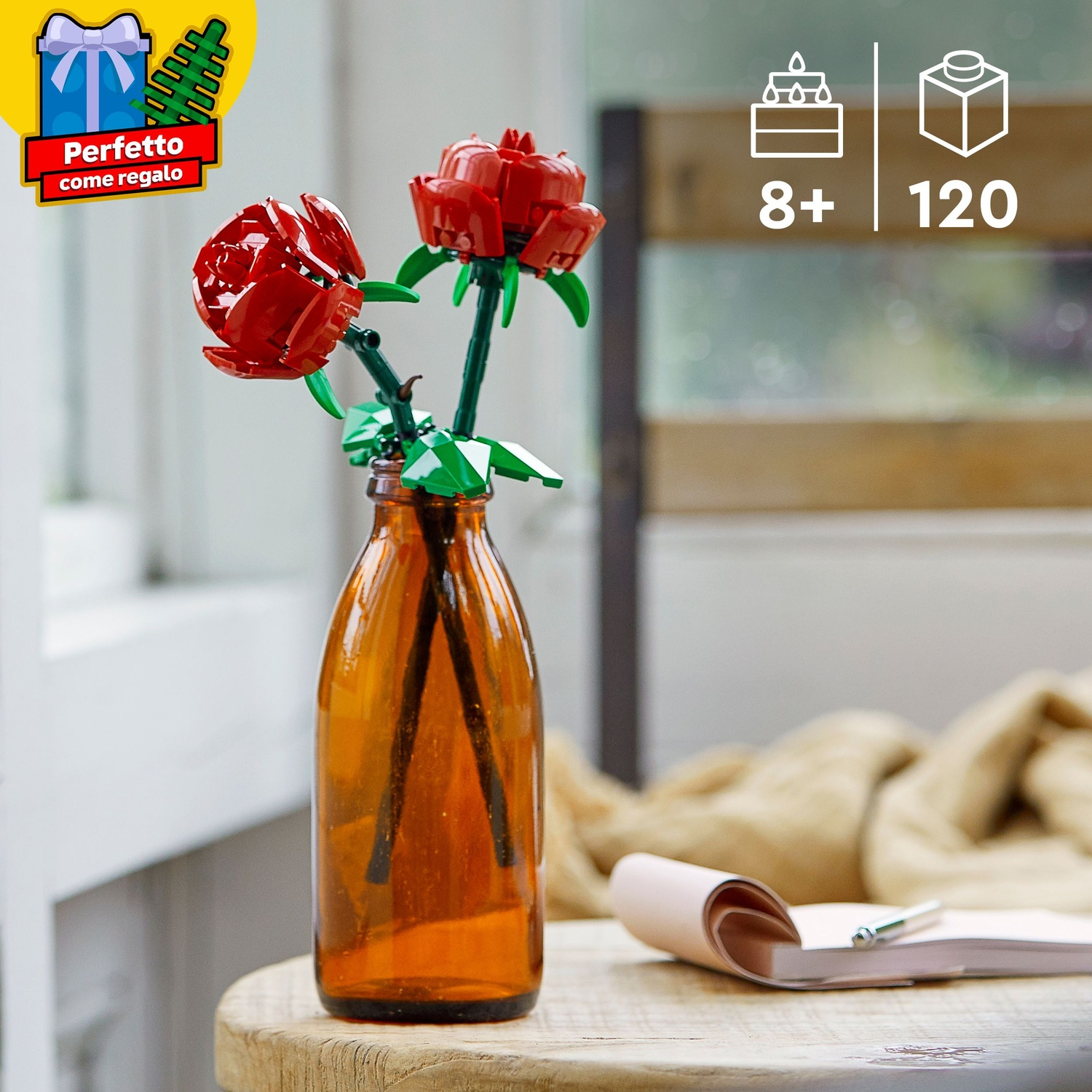 Due rose rosse Lego in una bottiglia di vetro marrone su tavolo legno.