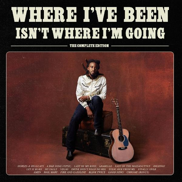 Mann in weißer Jacke sitzt auf Gepäck mit Gitarre. Albumtitel: Where I've Been Isn't Where I'm Going.