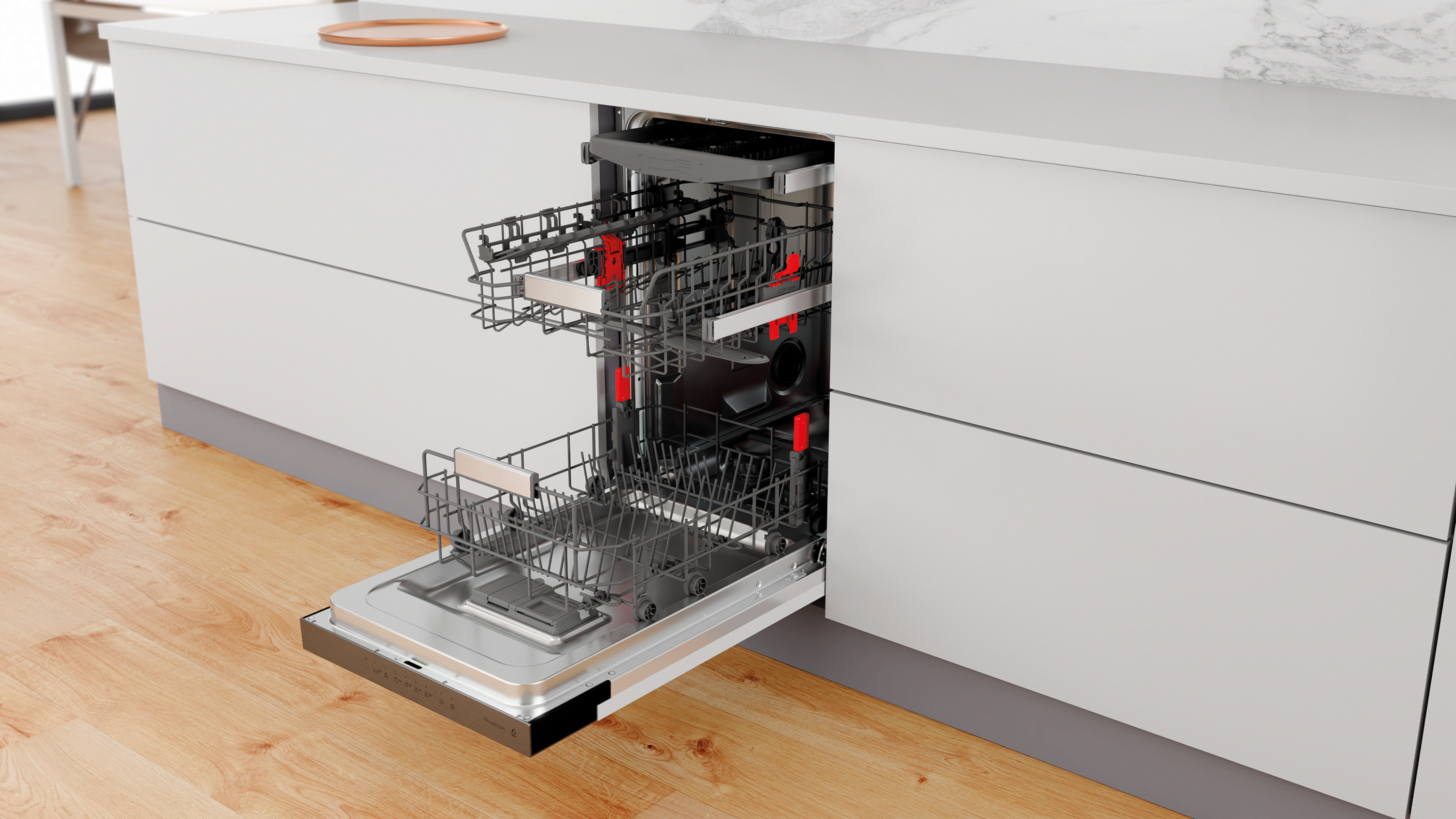 Otwarta zmywarka z dwoma koszami i czerwonymi detalami na drewnianej podłodze.