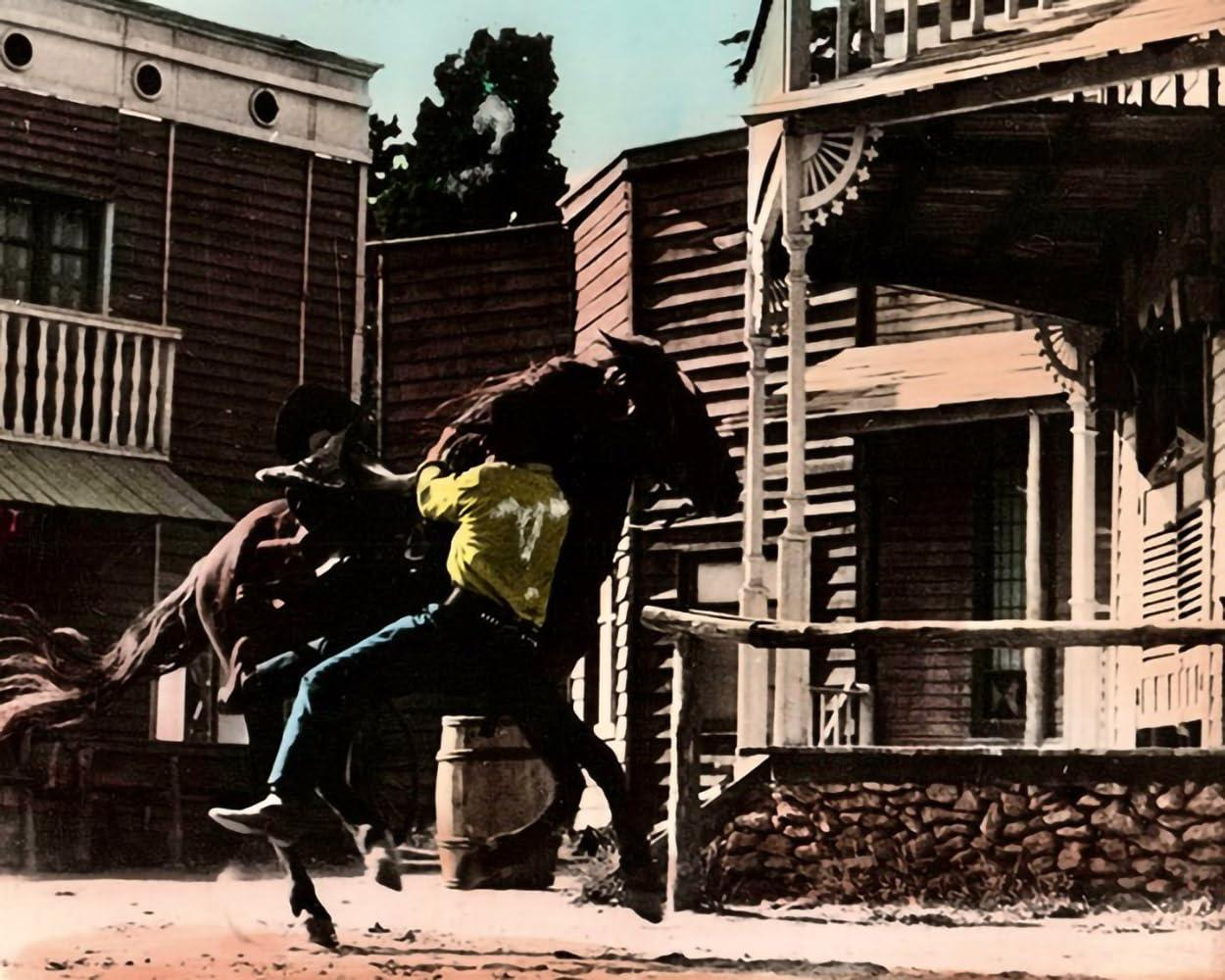 Ein Cowboy auf einem Pferd reitet durch eine staubige Stadtstraße.